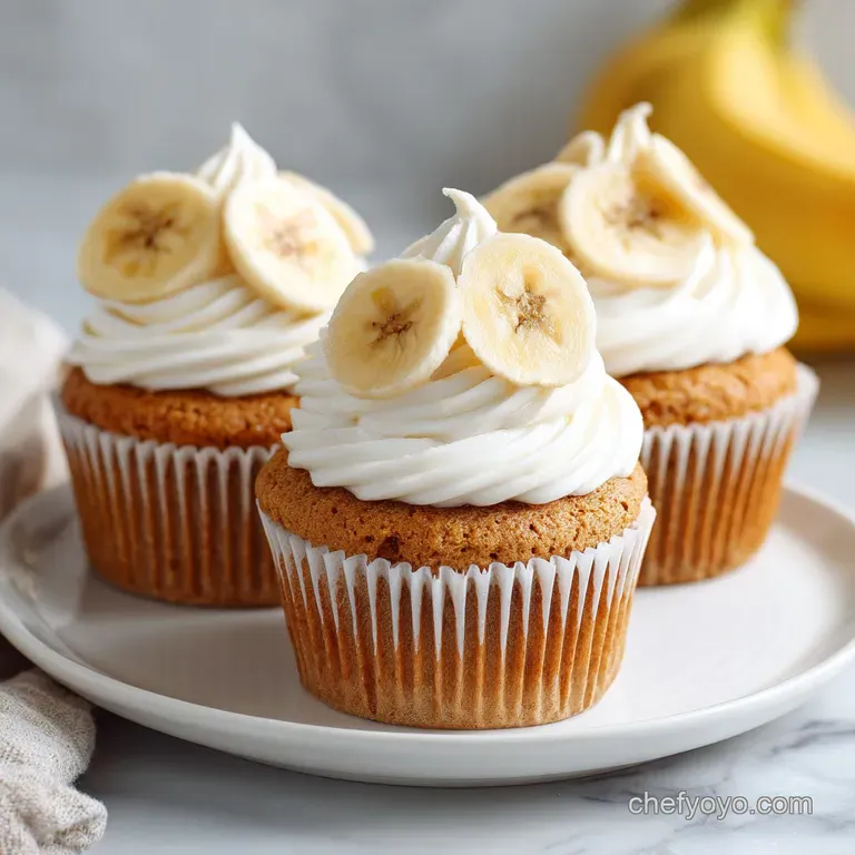 Three golden cupcakes on a white porcelain platter, topped with swirls of cream and dainty vanilla wafer cookies.