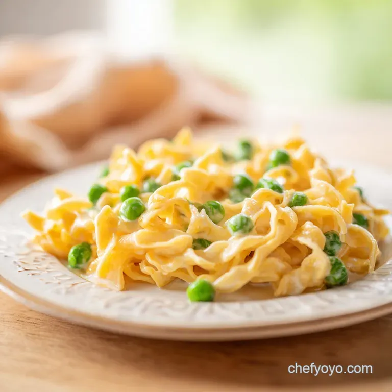 A generous scoop of creamy pasta with peas and melted cheese, garnished with fresh parsley on a white plate.