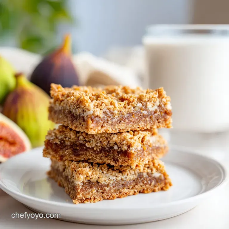 Two rustic fig bars sit on a plate, revealing a glimpse of the rich, dark fig filling and flaky crust.