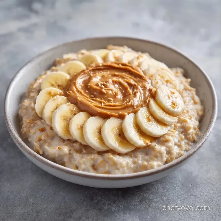 Warm porridge topped with fanned banana slices, a swirl of peanut butter, and a sprinkle of cinnamon on a wooden table.