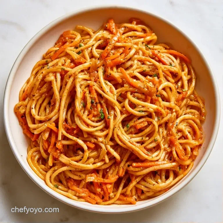 Twirled noodles with vibrant orange slivers and crisp green vegetables served in a modern ceramic dish.